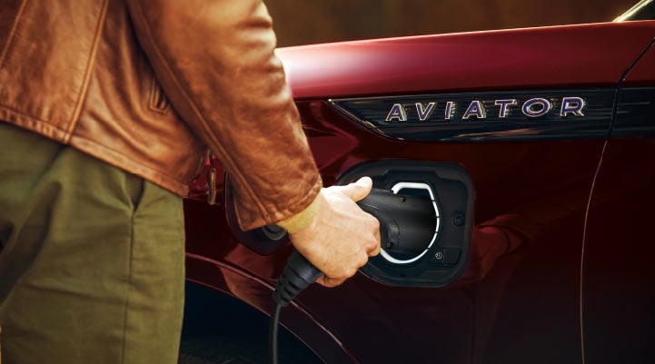 A hand is shown plugging in the charger into the charging port of a 2021 Lincoln Aviator | Jenkins & Wynne Lincoln in Clarksville TN